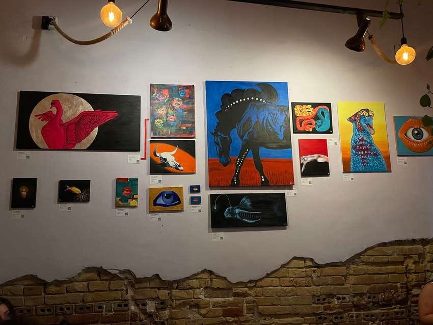 Wall of Laura's paintings hanging at Charbon Art Café